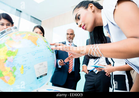 Business-Team diskutieren globale Expansionspläne Globus betrachten, indische, Caucasian, chinesischen und indonesischen Leute Stockfoto