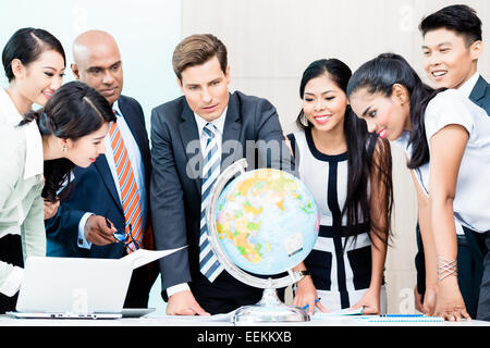 Business-Team diskutieren verfügbar Finanzinformationen für outsourcing-Pläne, die auf der Suche im Globe, Indisch, Kaukasier, Chinesen und In Stockfoto