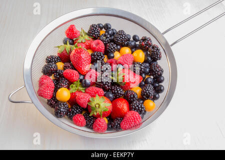 Gemischte Beeren der verschiedenen Arten, Farben und Formen in einem Sieb. Stockfoto
