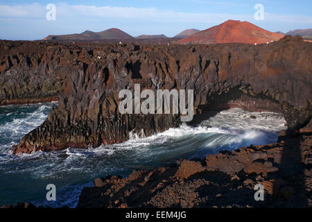 Felsige Küstenlinie, Los Hervideros, vulkanische Landschaft, Montañas del Fuego, die Feuerberge im Timanfaya Nationalpark zurück Stockfoto