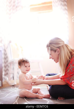 Babymädchen sitzen auf Boden mit Mutter zu Hause Stockfoto