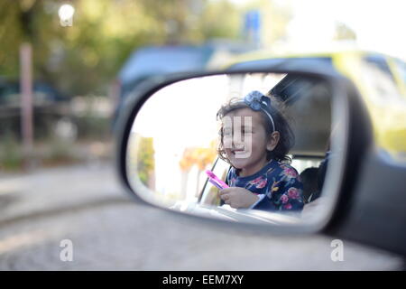 Mädchen (4-5) Autoreise genießen und suchen im Rückspiegel Stockfoto