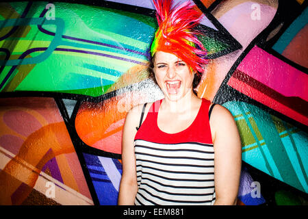 Kaukasischen Frau in bunte Perücke Lachen in der Nähe von Graffitiwand Stockfoto