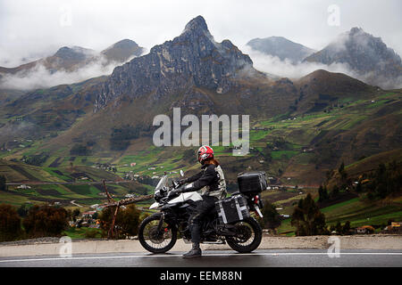 Mann auf einem Motorrad wartet an der Seite einer Bergstraße, Tigua, Pujilí, Cotopaxi, Ecuador Stockfoto