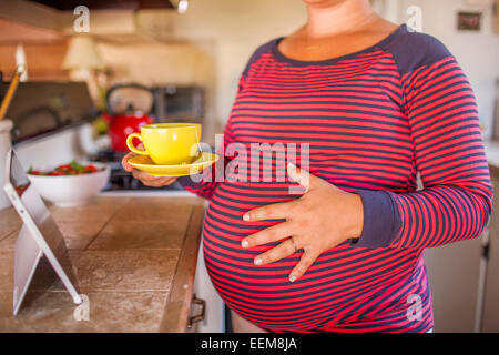 Schwanger kaukasischen Mutter Holding Tasse Tee in der Küche Stockfoto