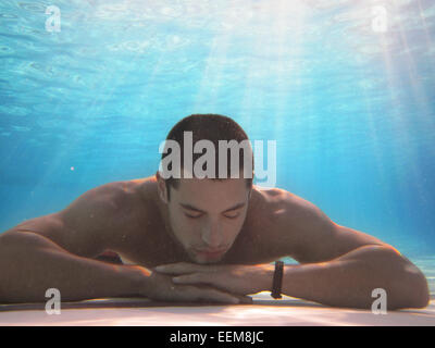 Mann unter Wasser liegt auf dem Boden eines Schwimmbades Stockfoto