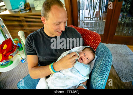 Kaukasische Vater hält Baby junge im Sessel Stockfoto