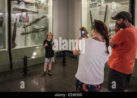 Museum-Erinnerungen an den Krieg. Eine Frau fotografiert ihren Sohn vor einem der Fenster, die Waffen, die von der US-Armee verwendet verfügbar machen. Stockfoto