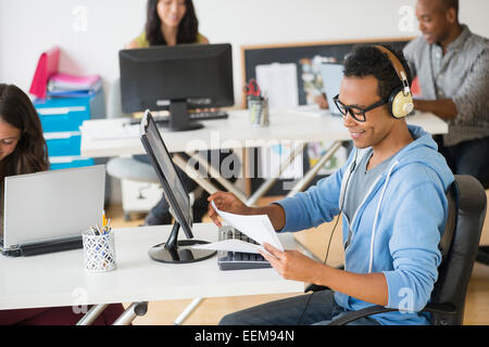 Geschäftsmann Kopfhörer hören und arbeiten im Büro Stockfoto