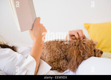 Kaukasische Frau liest mit Hund Stockfoto