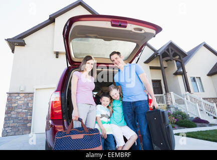 Kaukasische Familienholding Koffer mit dem Auto Stockfoto