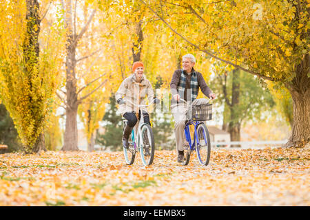 Ältere kaukasischen paar Fahrrad auf Blätter im Herbst Stockfoto