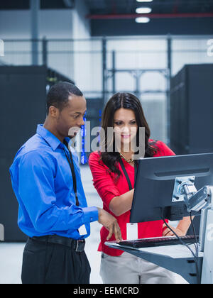 Geschäftsleute, die mit Computer im Serverraum Stockfoto