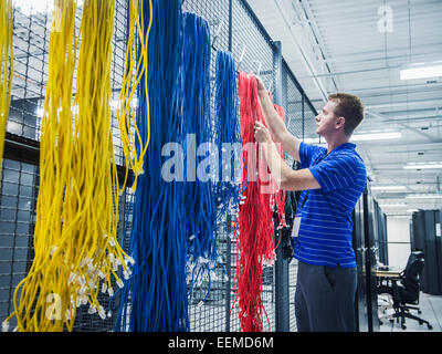 Kaukasische Techniker hängende Kabel im Serverraum Stockfoto