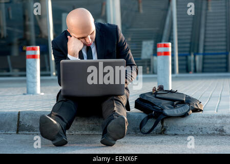 Geschäftsmann oder Banker arbeiten mit Laptop außerhalb des Flughafens oder zeitgenössische Gebäude Stockfoto