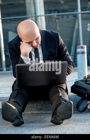 Geschäftsmann oder Banker arbeiten mit Laptop außerhalb des Flughafens oder zeitgenössische Gebäude Stockfoto