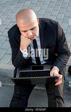 Geschäftsmann oder Banker arbeiten mit Laptop außerhalb des Flughafens oder zeitgenössische Gebäude Stockfoto