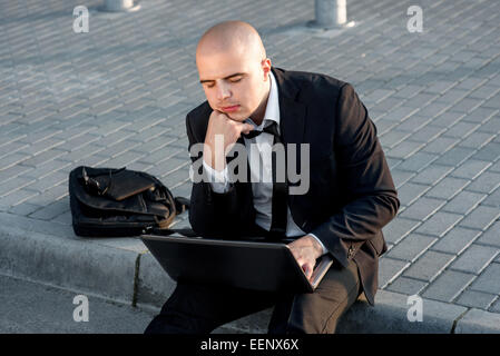 Geschäftsmann oder Banker arbeiten mit Laptop außerhalb des Flughafens oder zeitgenössische Gebäude Stockfoto