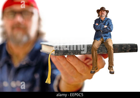 Mann mit Hut sitzt auf dem Buch auf dem weißen Hintergrund Stockfoto