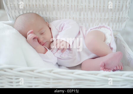 Schlafendes neugeborenes Mädchen in einem weißen geflochtenen Korb Stockfoto