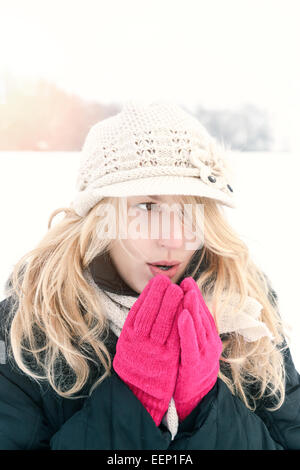 Winter-Frau im Schnee Foto, Schläge Atem ihre Hände außerhalb an kalten Wintertag. Porträt-kaukasischen weibliches Modell mit rosa Boxhandschuh Stockfoto