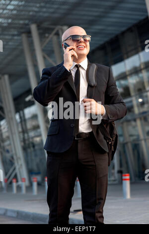 Kaufmann oder Bankier sprechen Telefon außerhalb des Flughafens oder der zeitgenössischen Gebäude Stockfoto