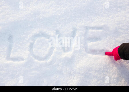 schriftliche oder per hand gezeichnet, in rosa Handschuh Wort Liebe auf weißen Schnee, romantische Bildkomposition. Menschliche Hand schreiben oder Zeichnen von Buchstaben Stockfoto