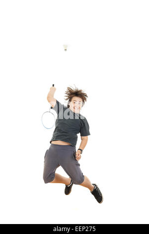 süße junge männliche mollig Kind oder junge lächelnd und Badminton-Schläger halten und versuchen, den Ball zu schlagen, beim Springen in Luft auf weißem Rücken Stockfoto