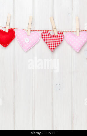 Valentinstag-Spielzeug-Herzen hängen am Seil über weißen hölzernen Hintergrund mit Textfreiraum Stockfoto
