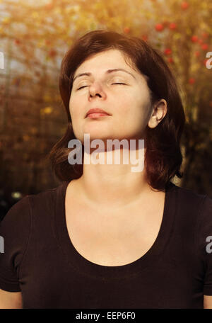 Nahaufnahme Portrait der schönen Frau lächelt mit geschlossenen Augen über Sonneneinstrahlung, Meditation im freien Stockfoto