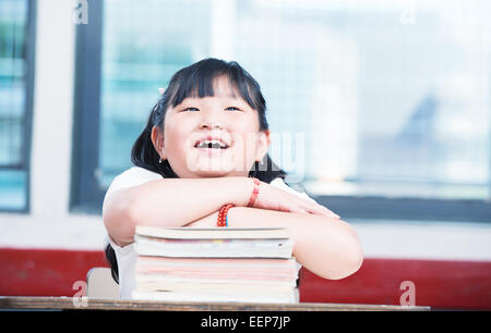 Porträt von niedlichen asiatische Mädchen auf Buch Stack auf der Suche nach oben. Schule Unterricht glücklich Szene. Stockfoto