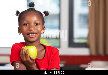 Afrikanische Mädchen an Schulbank bereit, ihr Apfel zu essen. Stockfoto