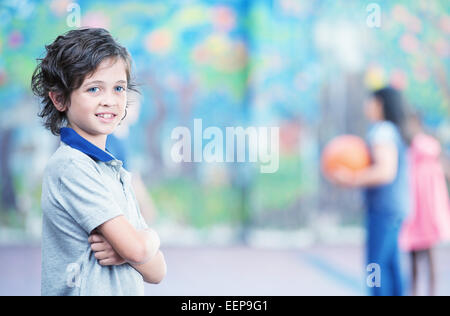 Glückliches Kind lächelnd im Schulhof mit anderen Chilldren spielen auf Hintergrund. Stockfoto