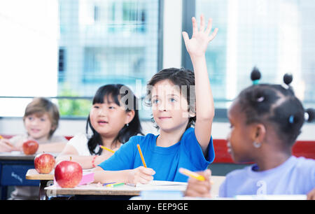 Gemischtrassig Klasse Grundschule. Kind, hob seine Hand bereit, zu beantworten. Stockfoto