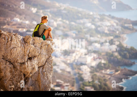 Junge Frau sitzt auf Felsen und genießen schöne Aussicht Stockfoto