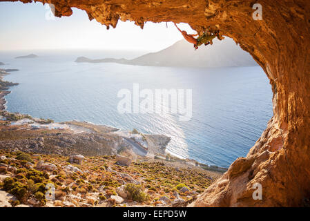 Männliche Kletterer Klettern auf einem Dach in einer Höhle bei Sonnenuntergang Stockfoto