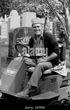 Friedhof Arbeitskraft einem Mähtraktor Reiten. Stockfoto