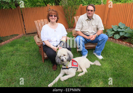 Frau mit RSD und ihre Begleithund mit Ehemann sitzt in ihrem Hinterhof Stockfoto