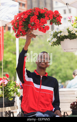 Mann im Rollstuhl mit spinale Meningitis shopping für Blumen auf einem Bauernmarkt Stockfoto