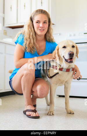 Frau mit Sehschädigung in Küche mit ihrem Servicehund Stockfoto