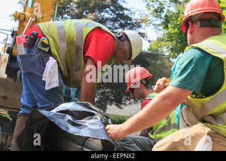 Platzieren Sie Bauarbeiter für Bagger heben Hauptwasserleitung in Vorbereitung Stockfoto