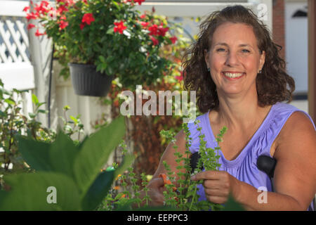 Frau mit Spina Bifida mit Krücken und schneiden Gartenblumen Stockfoto