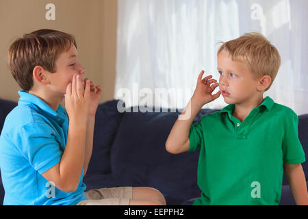 Jungen mit Hörschädigungen Unterzeichnung "Katze" in amerikanischer Gebärdensprache auf ihrer couch Stockfoto