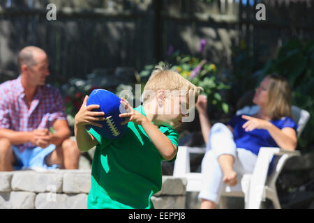 Jungen spielen Fußball und Eltern sitzen im Hintergrund mit Hörschädigungen Stockfoto