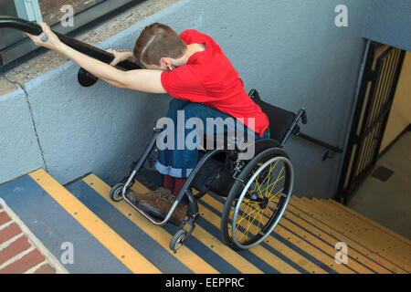 Trendige Mann mit einer Querschnittslähmung im Rollstuhl rückwärts u-Bahn Treppe hinunter Stockfoto