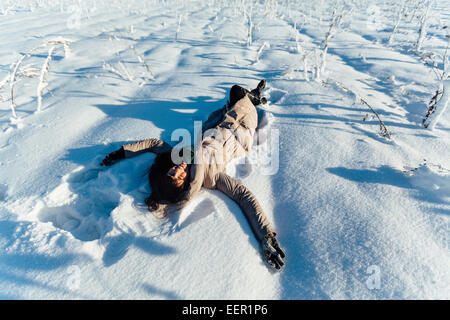 Schöne Brünette Mädchen lächelnd und liegen auf dem Schnee Stockfoto