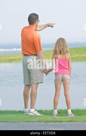 Vater und Tochter an einem See in einem Park zeigen Stockfoto