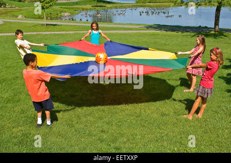 Kinder spielen mit dem Fallschirm Stockfoto