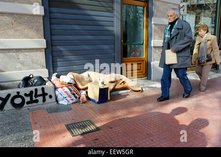 Athen, Griechenland. 21. Januar 2015. Griechen Fuß durch ein Obdachloser schlafen auf dem Bürgersteig in der Mitte von Athen. Die griechischen statistischen Behörde (ELSTAT) hat die nichtfinanziellen Konten für das 3. Quartal 2014 (Juli-September) veröffentlicht. Die Einnahmen aus Einkommens- und Vermögenssteuer sank im Vergleich zum gleichen Quartal 2013, während die Einnahmen aus Produktions- und Importabgaben fallen gelassen. Bildnachweis: Michael Debets/Alamy Live-Nachrichten Stockfoto