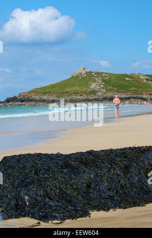 St Ives Cornwall: Mann in kurzen Hosen zu Fuß entlang Porthmeor Beach in St Ives in Cornwall Stockfoto